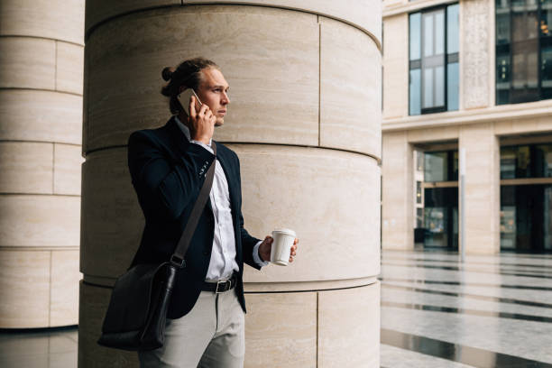 istock Stylish man talking on cell phone holding coffee 1289765364