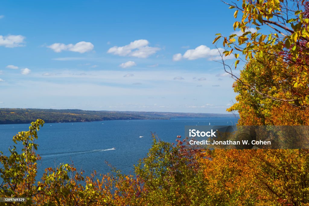 Watercraft navigate the waters of Cayuga Lake, which is one of the Finger Lakes in New York State, during a partly cloudy autumn day. New York State Stock Photo