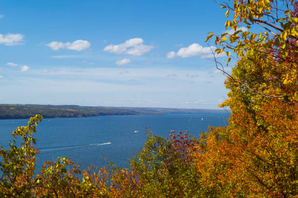 Watercraft navigate the waters of Cayuga Lake, which is one of the Finger Lakes in New York State, during a partly cloudy autumn day. stock photo