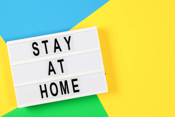 istock Lightbox with text STAY AT HOME on yellow, green and light blue background. Top view 1289769429