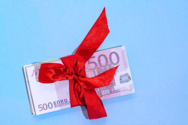 istock Euro banknotes five hundred on a stack with red bow on a blue background. Gift, bonus or reward concept. 1289771171