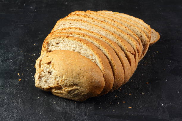 istock Isolate of white loaf of bread with sliced ​​pieces on a black background 1289771405