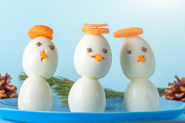Appetizer from boiled eggs and carrot. Funny snowmans. Kid's menu for Christmas and New Year