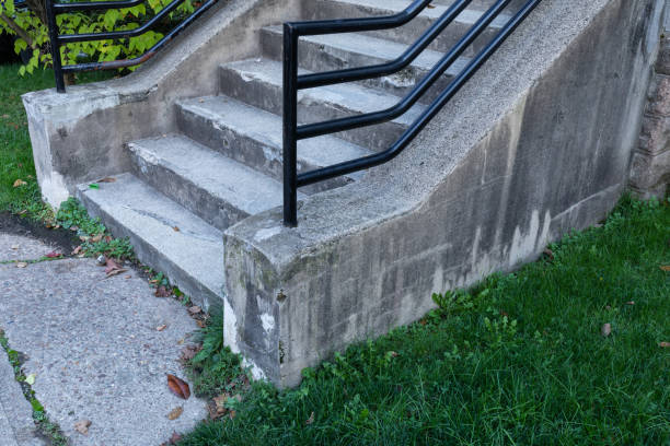 istock Weathered concrete stairs with heavy black pipe railing, grassy yard and concrete walkway 1289774722