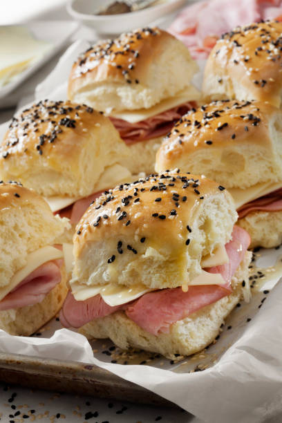 istock Preparing Baked Ham And Swiss Sliders on White Tray Buns 1289778900