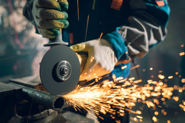 istock Locksmith in special clothes and goggles works in production. Metal processing with angle grinder. Sparks in metalworking 1289778914