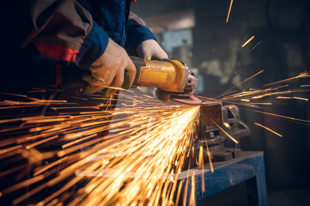 istock Locksmith in special clothes and goggles works in production. Metal processing with angle grinder. Sparks in metalworking 1289778997