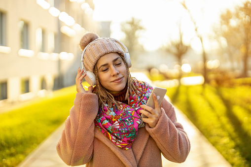 Portrait of young woman wearing warm winter coat and knit hat outdoors