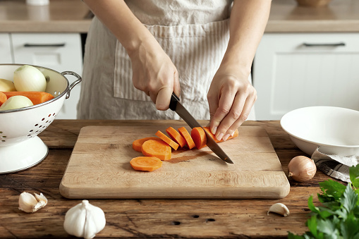 Woman in the kitchen preparing homemade food, female hands working with fresh vegetables