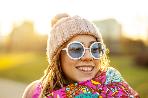 Portrait of young woman wearing warm winter coat, knit hat and scarf outdoors