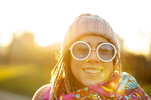 Portrait of young woman wearing warm winter coat, knit hat and scarf outdoors