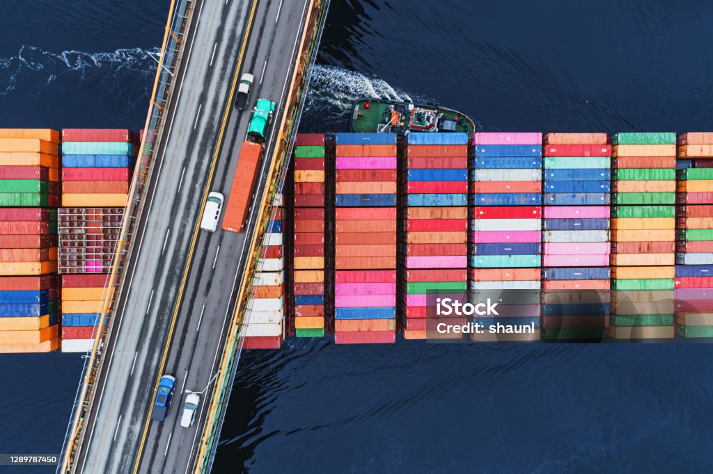 Outbound Container Ship A container ship passes beneath a suspension bridge as it departs for Europe. Freight Transportation Stock Photo