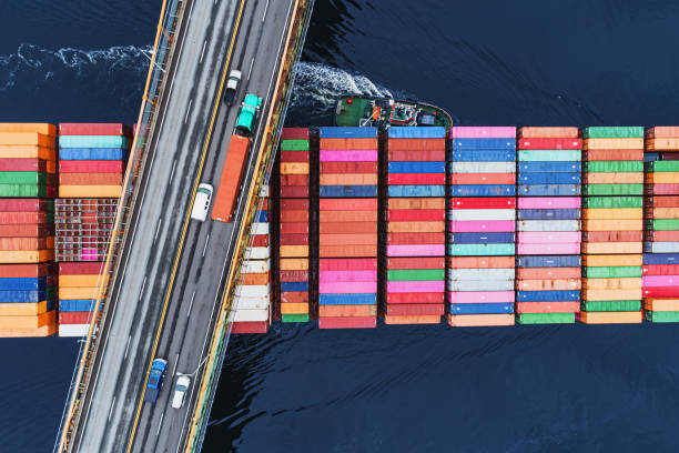 Outbound Container Ship A container ship passes beneath a suspension bridge as it departs for Europe. drone point of view stock pictures, royalty-free photos & images