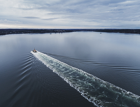 Aerial drone view of a tugboat enroute to aid a container ship.