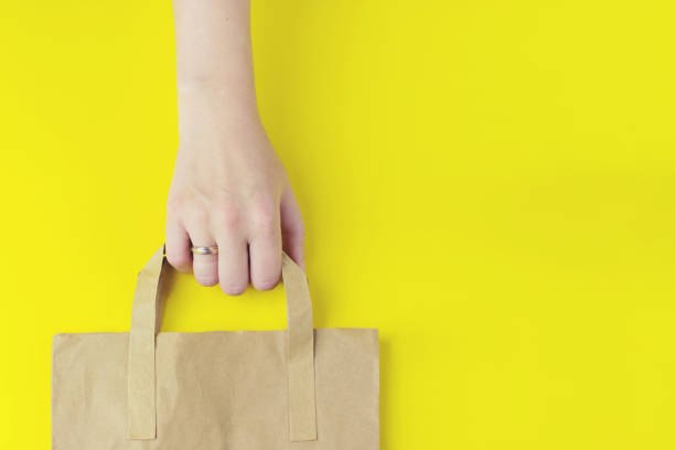 istock Brown clear empty blank craft paper bag for takeaway on the yellow background. Packaging template mockup. Delivery service concept. Copy space Advertising area. 1289788745