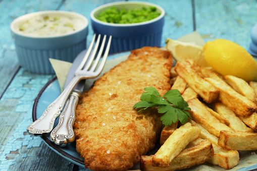 A closeup shot of Chicken schnitzel and fried potatoes on a plate over a marble background