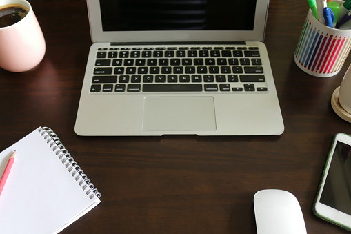 Stock photo showing a close-up view of a home office working desk with laptop and stationery. Working from home concept.