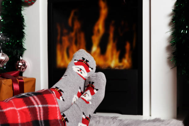 istock Woman sitting down and warms legs on fireplace at home 1289798635