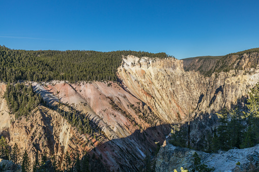 Late-afternoon shadows begin to creep up the steep walls of Yellowstone National Park's Grand Canyon of the Yellowstone.