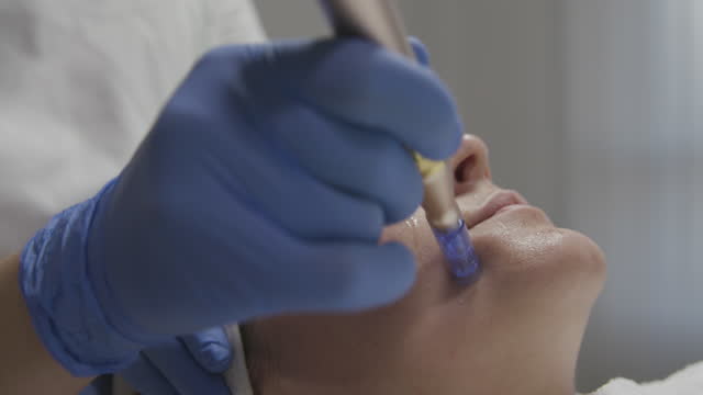 Beautician performing a needle mesotherapy treatment on a woman's face, close up