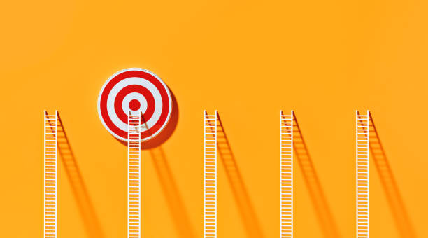 istock White Ladders Leaning on A Red Bull's Eye Target  on Yellow Wall 1289804091