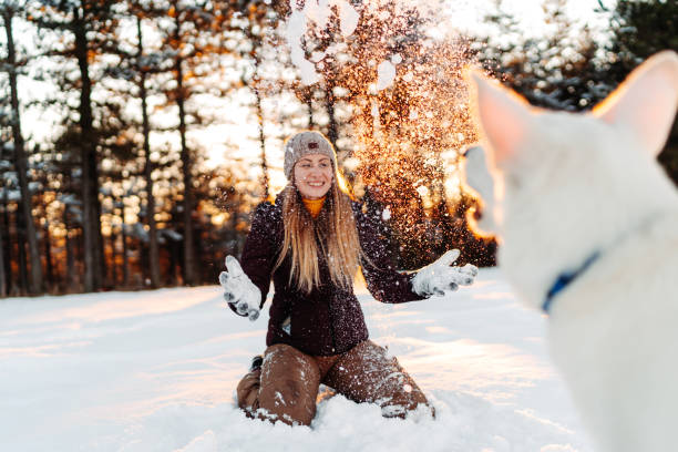 istock Young woman playing with dog on snow 1289804158