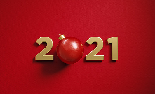A red Christmas bauble sitting between 2021 numbers  on red background. Horizontal composition with  copy space. 2021 new year concept.