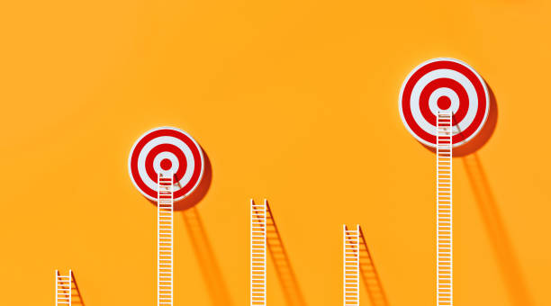 istock White Ladders Leaning on Two Red Bull's Eye Targets  on Yellow Wall 1289805128