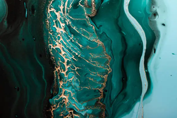 Photo of Acrylic Fluid Art. Dark green waves in abstract ocean and golden foamy waves. Marble effect background or texture