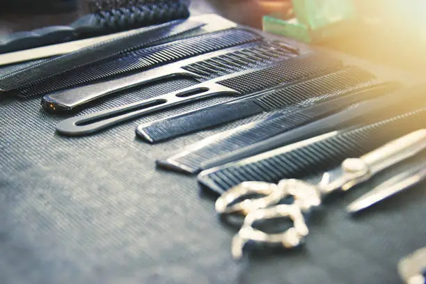 Combs, brushes and scissors on the table in the barbershop. Selective soft focus, lens glare