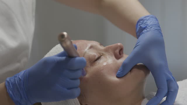Beautician performing a needle mesotherapy treatment on a woman's face, close up