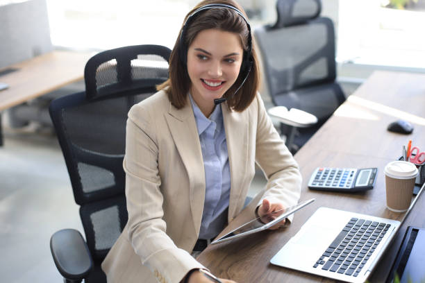 istock Cheerful female manager sitting at office desk and performing corporate tasks using wireless connection on digital gadgets. 1289830886