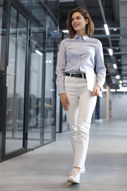 istock Businesswoman walking along the office corridor with documents. 1289830974