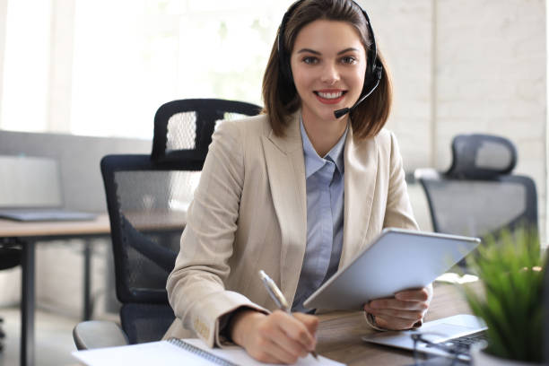 istock Cheerful female manager sitting at office desk and performing corporate tasks using wireless connection on digital gadgets. 1289831329