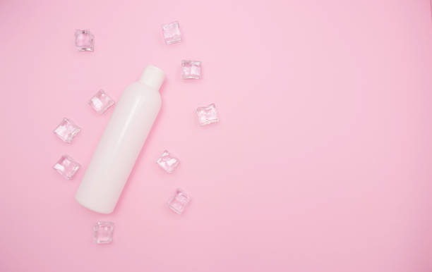 istock White plastic bottle for shampoo or other cosmetics. Ice cubes around, pink background, free space for text, top view. 1289832528