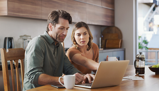 Shot of a young couple using a laptop while going over their finances together at home