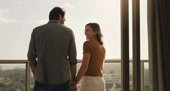 Shot of a happy couple standing together on a balcony