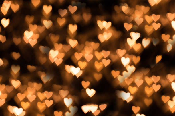 fundo desfocado, bokeh na forma de um coração de cor amarela quente - valentines day hearts flash - fotografias e filmes do acervo