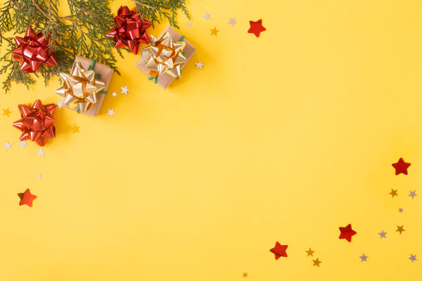 fond plat de noël. boîtes de cadeau avec des paillettes, des décorations et des confettis d’étoile sur le jaune - joueur de champ gauche photos et images de collection