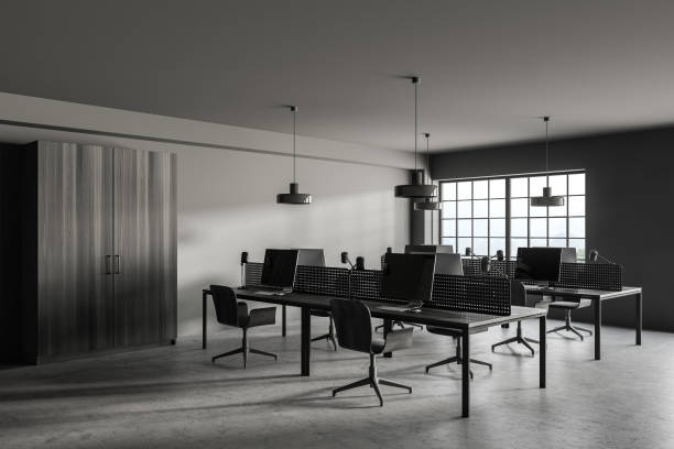istock Stylish gray open space office corner with wooden tables and wardrobe 1289853930