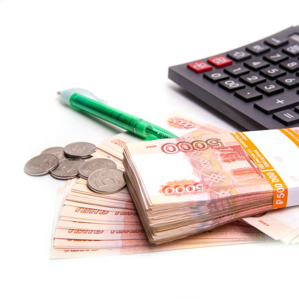 istock Coins with Russian banknotes, calculator and pen isolated on a white background, panoramic banner format, close-up, space for text 1289854143