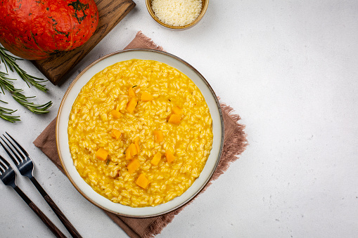 Pumpkin risotto on white table with contrast napkin. Copy space. Flat lay, top view.