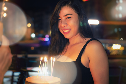 Cheerful woman holding birthday cake with candle