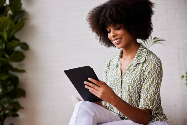 istock Smiling young woman sitting at home using a digital tablet 1289857550