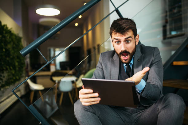 istock Worried young businessman looking at tablet inside modern office 1289860730