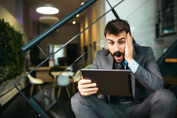 istock Worried young businessman looking at tablet inside modern office 1289861663