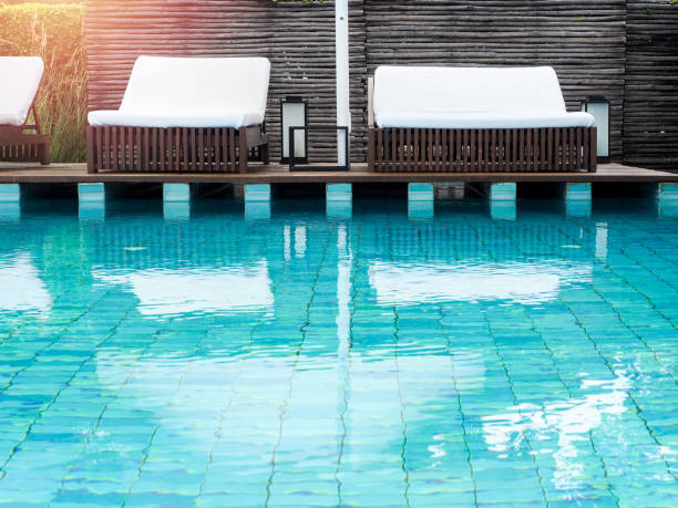 istock Empty white clean sunbeds on wood terrace near swimming pool. 1289865769