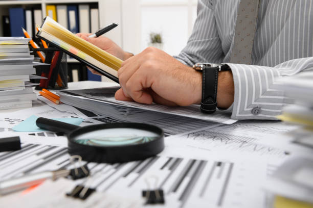 istock business concept - businessman working with reports in office, table and workspace close view, analyzing financial data, writes and counts 1289865777