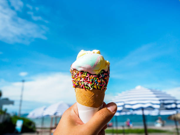 istock Ice cream in hand on beach and blue sky background. 1289865866