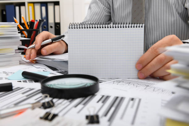 istock business concept - businessman working with reports in office, table and workspace close view, analyzing financial data, writes and counts 1289866012